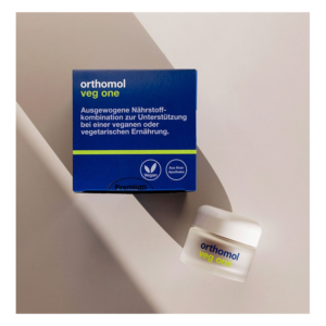Blaue Verpackung mit der Aufschrift 'orthomol veg one', unterstützt vegane Ernährung, zusätzlich ein kleiner Behälter daneben.