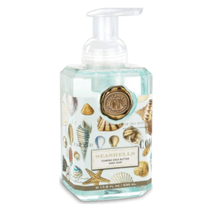 Seifenspender mit schaumiger Sheabutter, verziert mit Muschel-Motiven und einem goldenen Emblem.