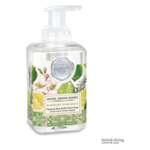 Seifenspender mit schaumigem Shea-Butter-Handseife, dekoriert mit frischen Kräutern und Limettenmotiven.