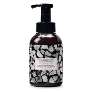 Braunglastiegel mit schwarzer Pumpe und Holzscheit-Design, enthält Schaumseife mit Sheabutter und würzigem Duft.