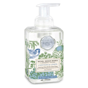 Transparente Flasche mit schaumigem Shea-Butter-Händeseife in der Duftrichtung Baumwolle & Leinen, dekoriert mit Pflanzenmotiven und einem Vogel.